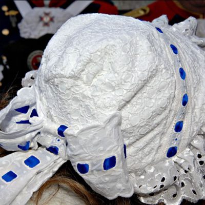 Eine aufwendig verzierte weiße Haube mit blauen Details symbolisiert die traditionelle Feier der Beueler Weiberfastnacht.